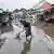 Man fishing out items from flood waters resulting from heavy rain in Bali, Indonesia