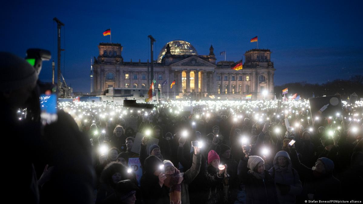 Demonstrators against right-wing extremism in front of the Reichstag building lighting up the night with their cell phone torches, January 2024
