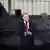 Ein Mann in einem dunklen Anzug, der polnische Präsident Karol Nawrocki, steht an einem Mikrofon. Im Hintergrund ist verschwommen ein Kampfflugzeug zu erkennen