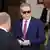 Scott Bessent, con gafas de sol y traje, con dos hombres que están de espaldas.