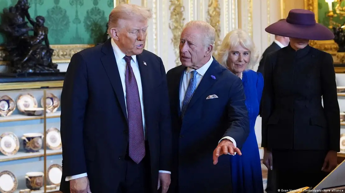 El rey británico, junto a la reina Camila y a la primera dama estadounidense Melania, gesticula mientras explica algo a Donald Trump.