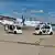 Zwei autonom fahrende Wagen stehen vor einer Propellermaschine auf dem Flughafen Paderborn
