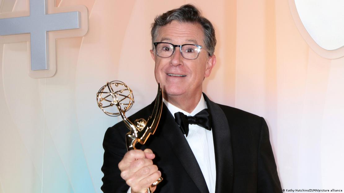 Stephen Colbert im Anzug mit einer Emmy-Trophäe in der Hand