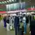 Pessoas em aeroporto frente a painel com informações sobre voos