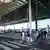 Pessoas com malas de rodinha passando por faixa de pedestres em frente à entrada do aeroporto de Berlim