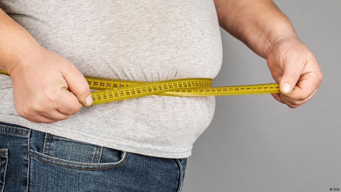 Belinin çevresini ölçen göbekli bir erkek 
