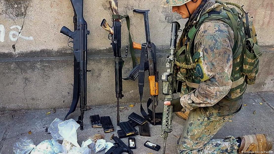 Militar em frente a armas apreendidas durante operação policial Militar em frente a armas apreendidas durante operação policial