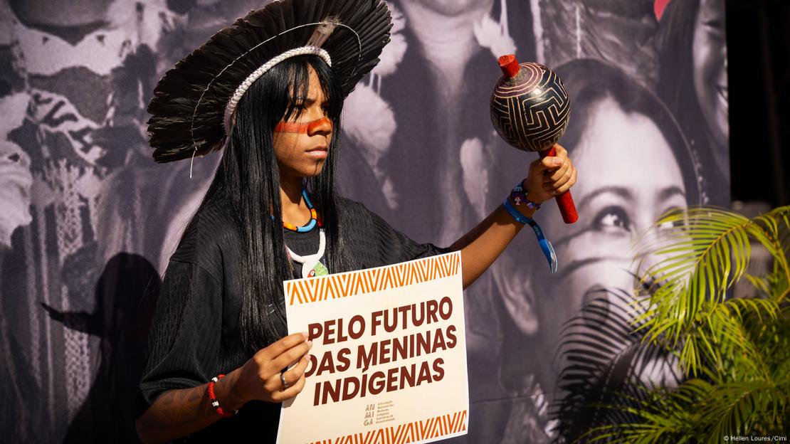 Mulher indígena segura cartaz em que se lê: "Pelo futuro das meninas indígenas"