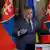 Robert Fico steht vor zwei Landesflaggen 