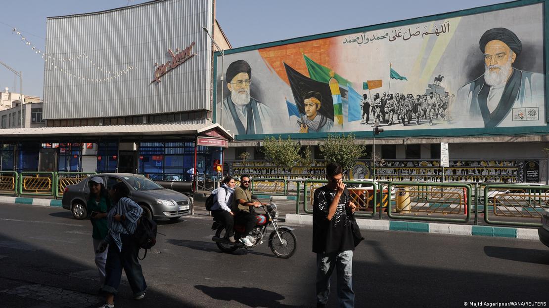 İran'ın başkenti Tahran'da bir sokakta, İran'ın dini lideri Ayetullah Ali Hamaney'in duvar resminin önünden geçen insanlar.