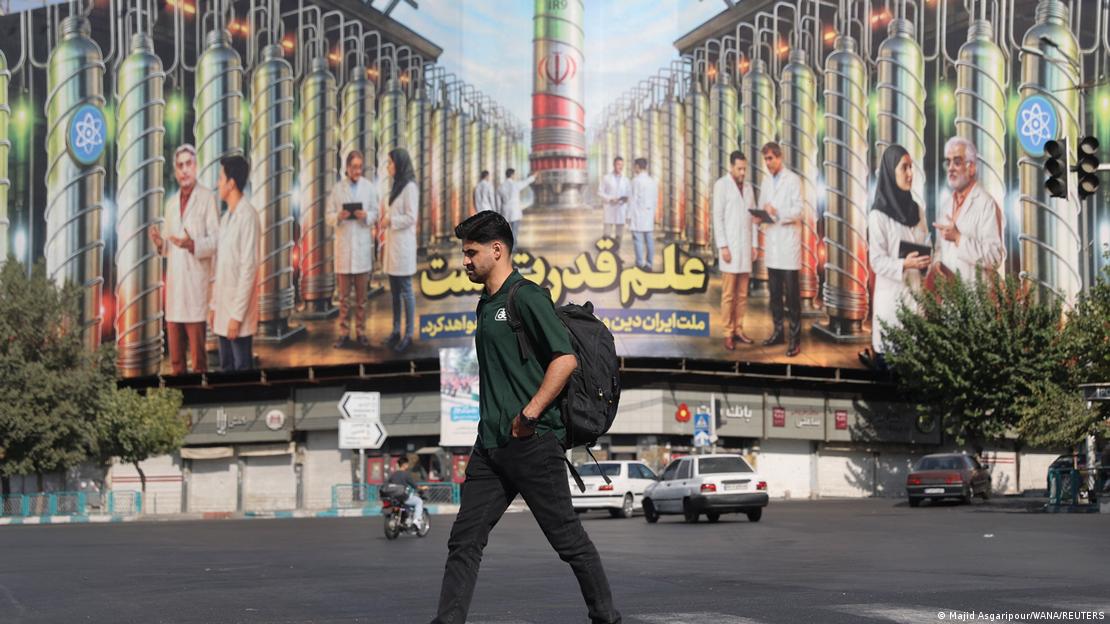 Tahran'da nükleer santrifüjlerin görüldüğü bir poster önünden yürüyen bir kişi