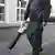 Two men use leaf blowers on a Zurich street