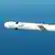 A white Tomahawk cruise missile is seen mid-flight against a blue sky