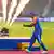Indian captain Suryakumar Yadav pretends to hold up a trophy with fireworks going off behind him