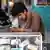 A man sits at a money changing counter and checks his smartphone in Kabul in June, 2025.
