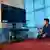 Dois jovens afegãos observam tela escurecida de televisão sem conectividade