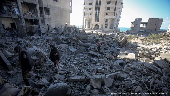 Mujeres palestinas caminando entre las ruinas.