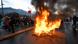 Hoguerra en mitad de una carretera. Al lado, personas en el marco de una protesta en Ecuador. Hoguerra en mitad de una carretera. Al lado, personas en el marco de una protesta en Ecuador.