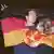 young couple on October 3, 1990 holding a black, red and gold GDR flag with the hammer, compass, and ear of corn cut out