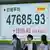 People walk in front of a screen displaying Japan's Nikkei share average in Tokyo, Japan, October 6, 2025