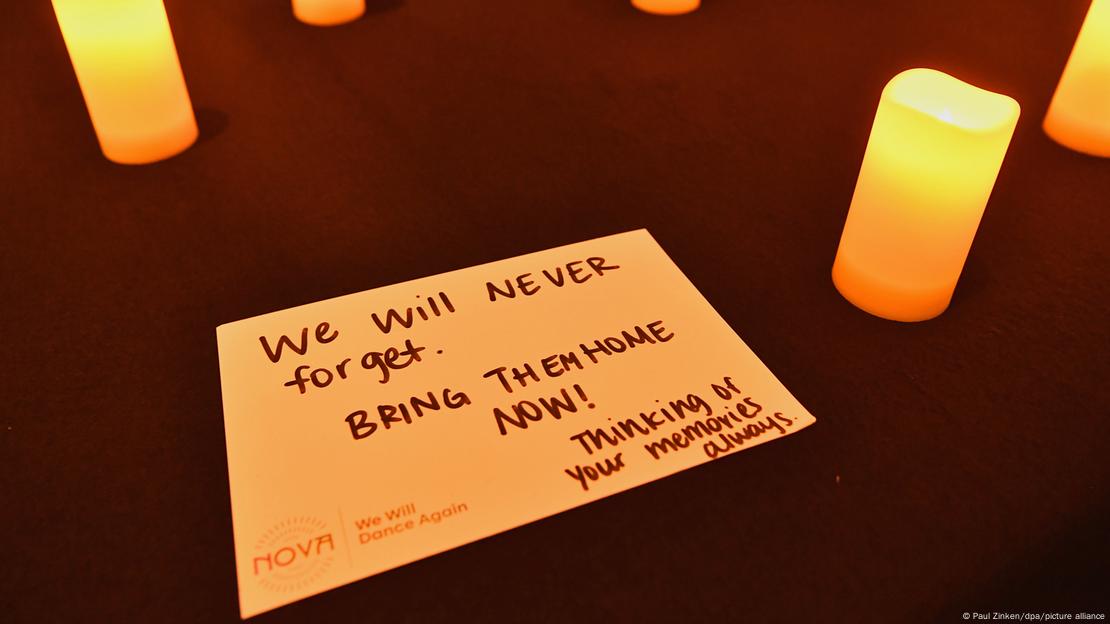 Lilin-lilin dinyalakan di sekeliling kartu bertuliskan 'Kami tidak akan pernah lupa. Bawa mereka pulang sekarang!'