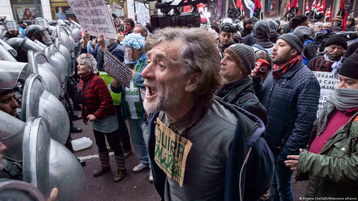 Imagen del 23.07.2025: organizaciones de jubilados, trabajadores y personas con discapacidad marchan desde el Congreso hasta la Plaza de Mayo, en medio de un masivo operativo policial. A la izquierda, los escudos de las de seguridad, alineados. A la derecha, los manifestantes. En primer plano, un hombre mayor con un cartón al cuello con un mensaje, vocea algo con la boca abierta. Imagen del 23.07.2025: organizaciones de jubilados, trabajadores y personas con discapacidad marchan desde el Congreso hasta la Plaza de Mayo, en medio de un masivo operativo policial. A la izquierda, los escudos de las de seguridad, alineados. A la derecha, los manifestantes. En primer plano, un hombre mayor con un cartón al cuello con un mensaje, vocea algo con la boca abierta.