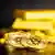 Monedas doradas de bitcoin con lingotes de oro en el fondo 