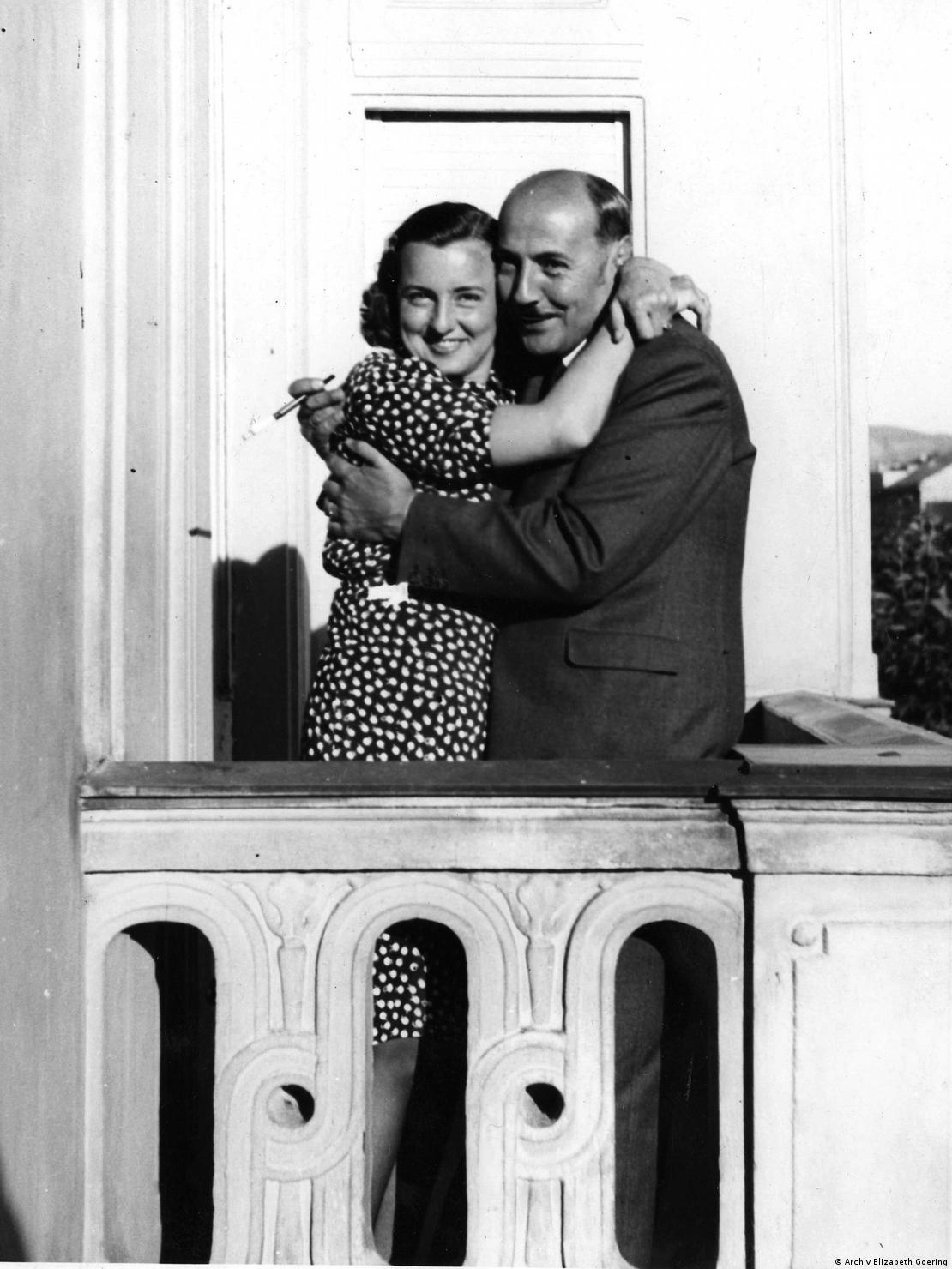 Black and white picture of a smartly dressed smiling couple in an embrace.