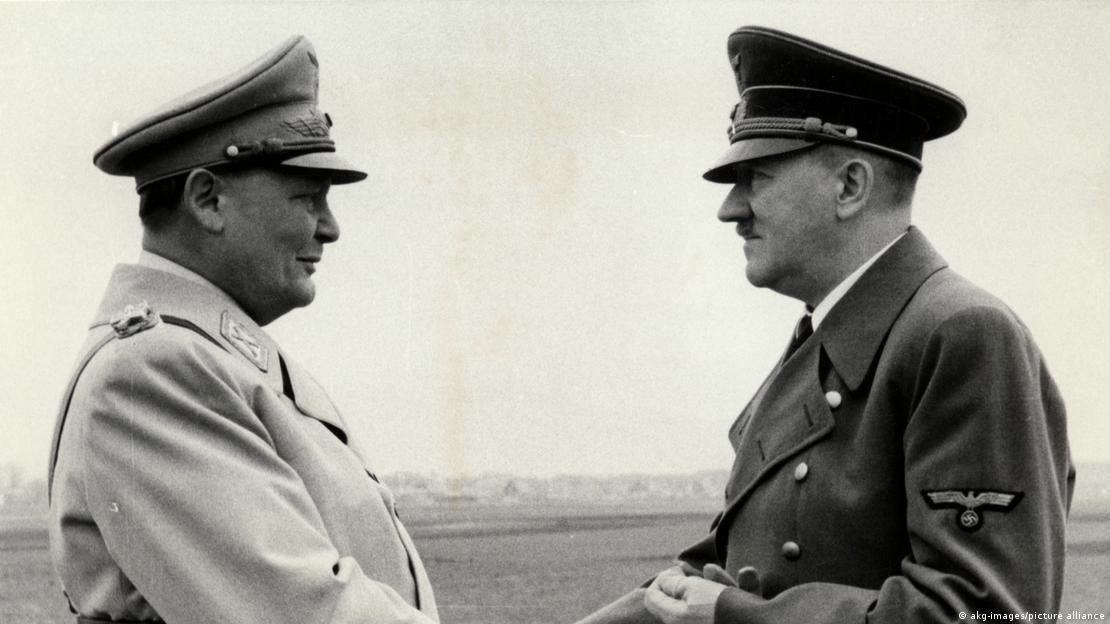 Black and white picture of two men in full military uniform shaking hands.