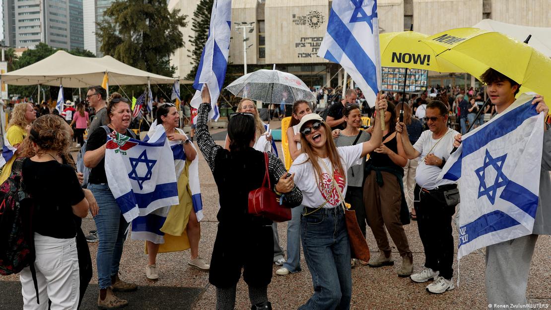Personas festejando en la calle con paraguas amarillos y banderas de Israel. Personas festejando en la calle con paraguas amarillos y banderas de Israel.
