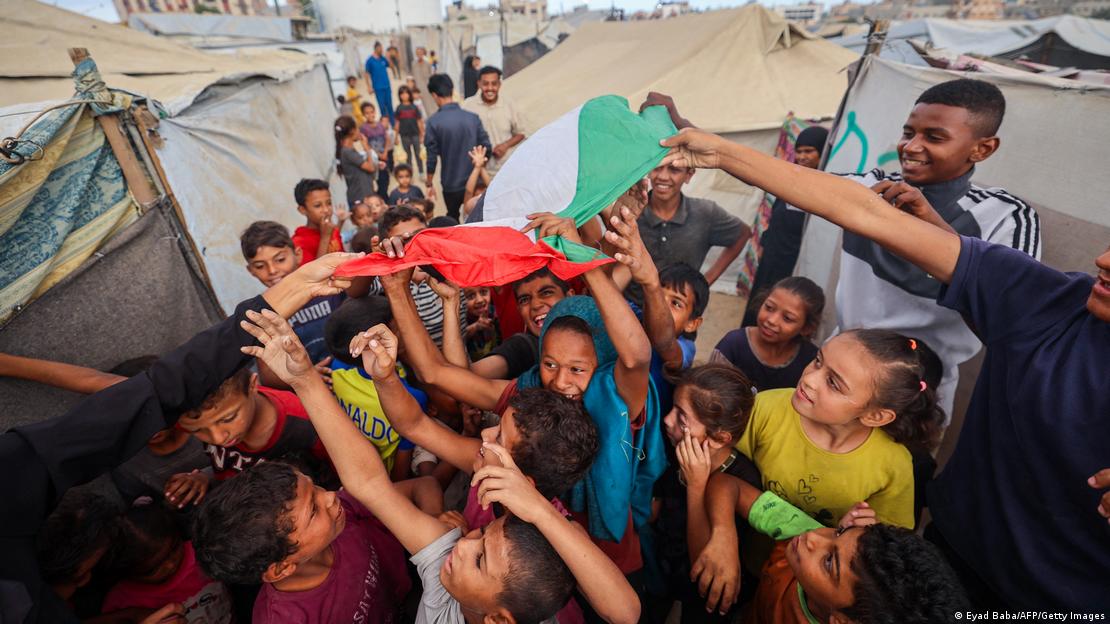 İsrail ile Hamas arasında sağlanan ateşkesin duyurulmasının ardında Gazze'de ellerinde Filistin bayrağı ile kutlama yapan çocuklar.