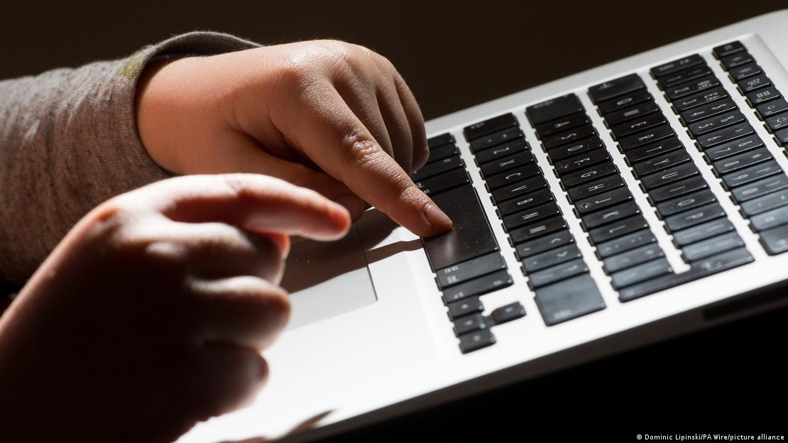 Manos infantiles sobre el teclado de un ordenador portátil.