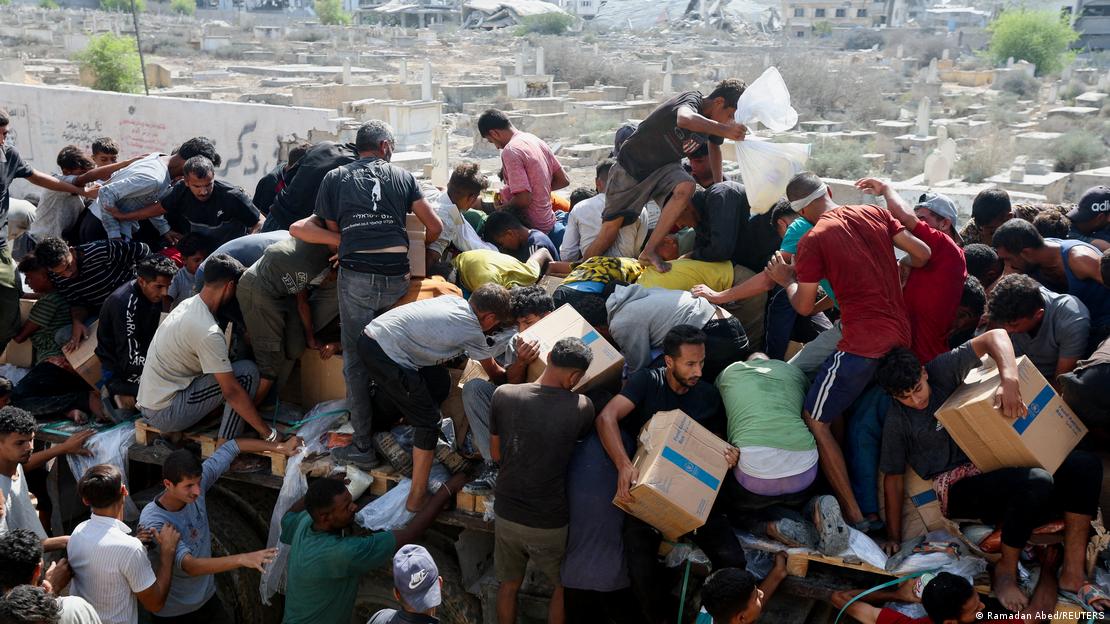 Palestinos recolhem caixas de ajuda humanitária de caminhão Palestinos recolhem caixas de ajuda humanitária de caminhão