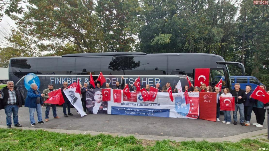 Bir otobüsün önünde, ellerinde Türk bayrağı, CHP bayrağı ve Atatürk posterleri olan insan kalabalığı