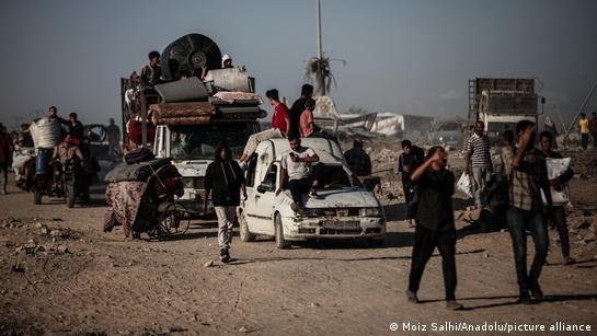Palestinos caminham por uma estrada carregando seus pertences.