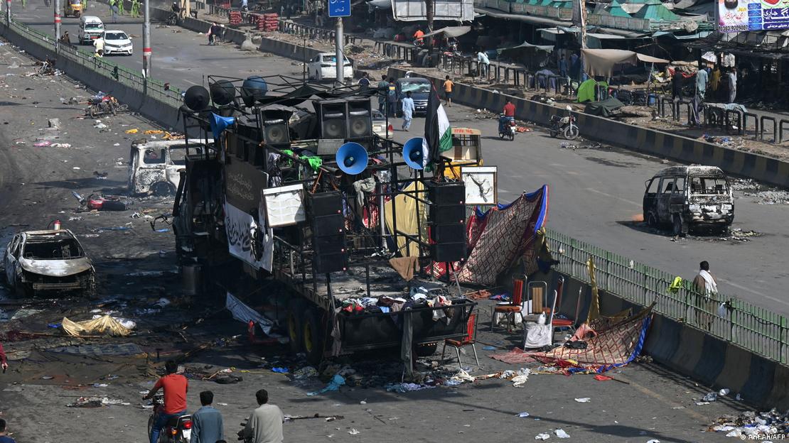 مریدکے میں پولیس اہلکاروں اور ٹی ایل پی کے اسرائیل مخالف مظاہرین کے درمیان پرتشدد جھڑپوں کے بعد جلی ہوئی گاڑیوں کے ملبے کے قریب سے مقامی افراد گزرتے ہوئے