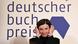 Dorothee Elmiger pulls her hair back in front of a wall that reads 'deutscher buch preis' (German Book Prize). Dorothee Elmiger pulls her hair back in front of a wall that reads 'deutscher buch preis' (German Book Prize).