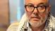 A middle-aged person wearing glasses and a graying beard poses for the camera A middle-aged person wearing glasses and a graying beard poses for the camera