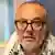 A middle-aged person wearing glasses and a graying beard poses for the camera