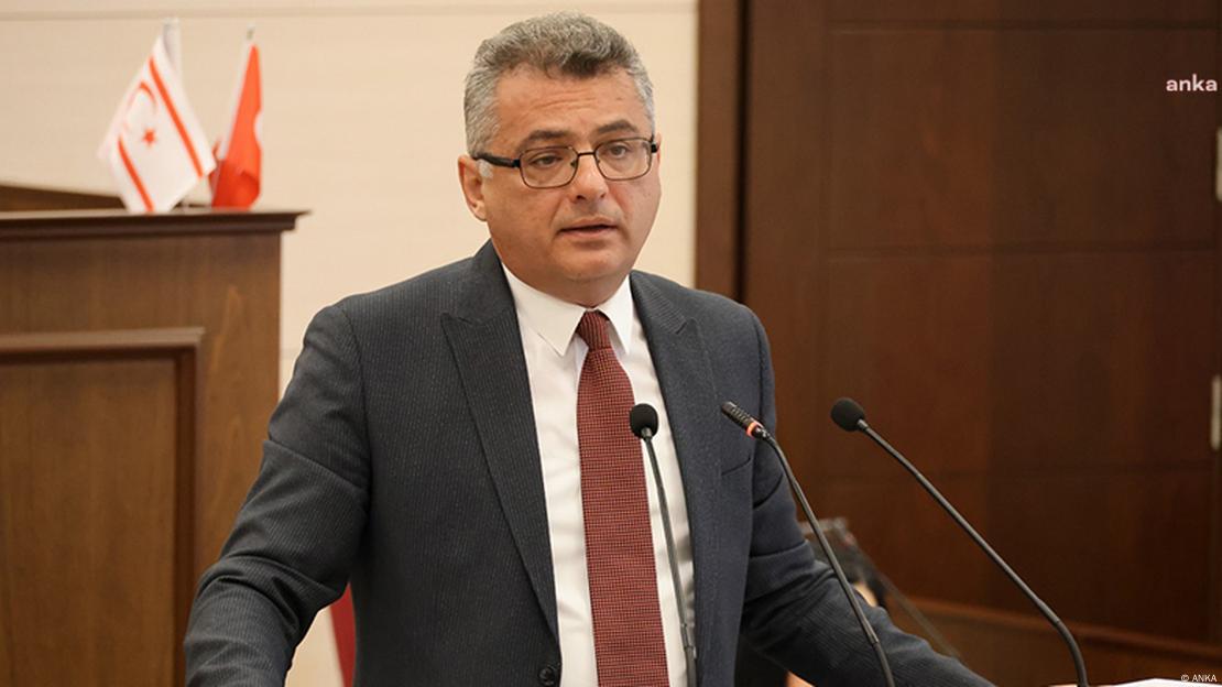 Meclis kürsüsünde konuşma yapan Tufan Erhürman. Arkasında KKTC ve Türkiye bayrakları görünüyor.