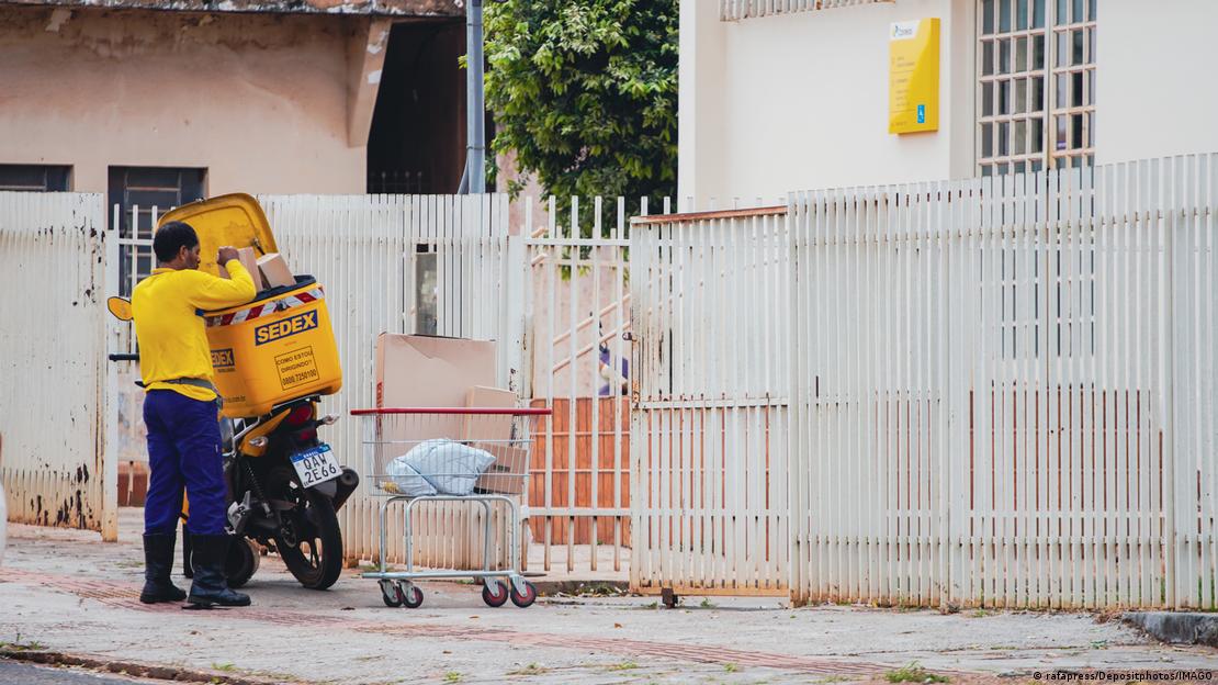 Carteiro do Correios coloca encomendas em moto