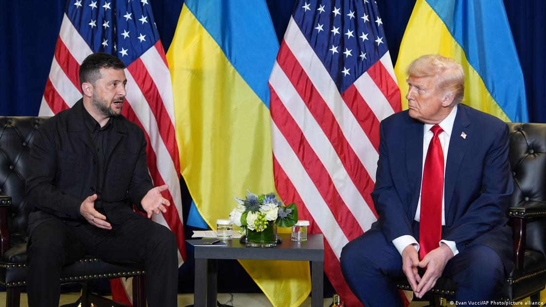 Wolodymyr Selenskyj und Donald Trump sitzen an einem kleinen Tisch bei der UN-Generalversammlung in New York im September 2025. Im Hintergrund stehen ukrainische und amerikanische Flaggen.