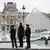 Police officers stand near the pyramid of the Louvre museum after reports of a robbery, in Paris, France on October 19, 2025