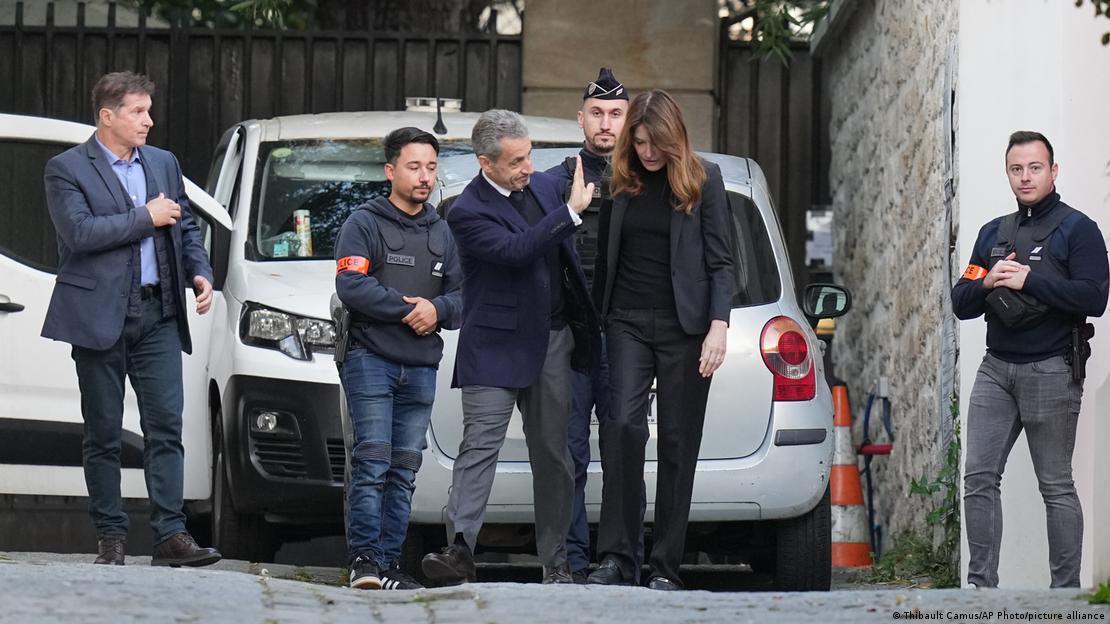 Sarkoz kendisini uğurlayanlara el sallıyor. Yanında eşi Carla Bruni ve polis memurları var Sarkoz kendisini uğurlayanlara el sallıyor. Yanında eşi Carla Bruni ve polis memurları var