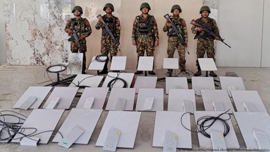 Beş silahlı Myanmar askeri, el konulduğu anlaşılan iletişim ekipmanlarının arkasında yan yana duruyor