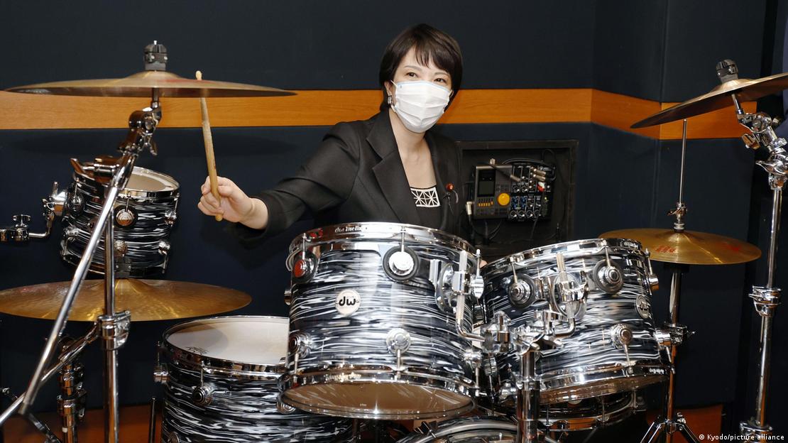 A primeira-ministra do Japão, Sanae Takaichi aparece de máscara, tocando bateria.