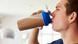 Ein junger Mann trinkt einen Protein-Shake aus einem Trinkbecher Ein junger Mann trinkt einen Protein-Shake aus einem Trinkbecher