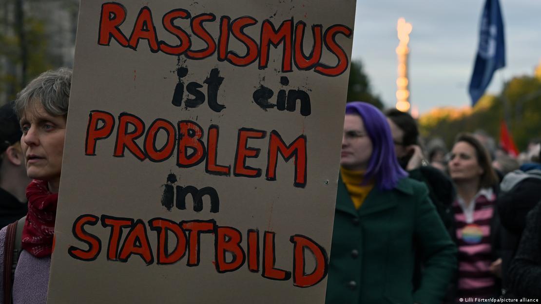 Demonstranten mit einem Schild, auf dem steht: Rassismus ist ein Problem im Stadtbild 
