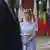 A woman in a pale blue dress (EU foreign and security policy representative Kaja Kallas) looks at her watch