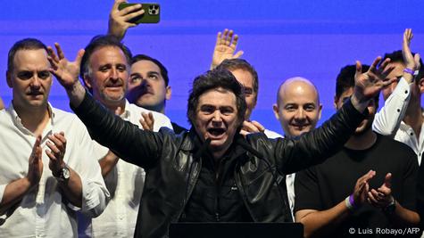 El presidente argentino se dirige a sus seguidores con los brazos abiertos y a voz en grito con parte de su equipo detrás aplaudiendo. El presidente argentino se dirige a sus seguidores con los brazos abiertos y a voz en grito con parte de su equipo detrás aplaudiendo.